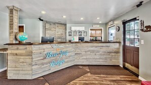A reception desk at Blue Jay Lodge with a wooden design, a globe, and a computer. - Blue Jay Lodge (South Lake Tahoe)