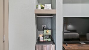 A compact kitchenette with a coffee machine, a small refrigerator, and a shelf with toiletries. - Blue Jay Lodge (South Lake Tahoe)
