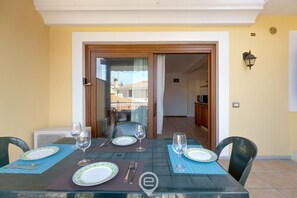 A dining table set with plates, cutlery, and glasses, with chairs around it. - Mirto 3 Apartment (Santa Maria Navarrese)