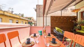 A dining area with a long table, orange chairs, and a wooden partition with string lights. - La Terrazza della Marina (Cagliari)