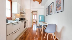 A compact kitchen with white cabinets, a microwave, and a sink. There is a dining area with a table and chairs. - La Terrazza della Marina (Cagliari)