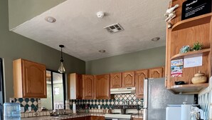 Una cocina con armarios de madera, salpicadero de azulejos, una isla grande con taburetes y dispensador de agua.