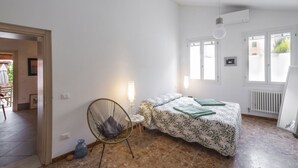 A bedroom with a bed, a chair, a table, and a radiator.