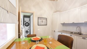 A compact kitchen with white cabinets, a sink, and a dining area with a table set for two.