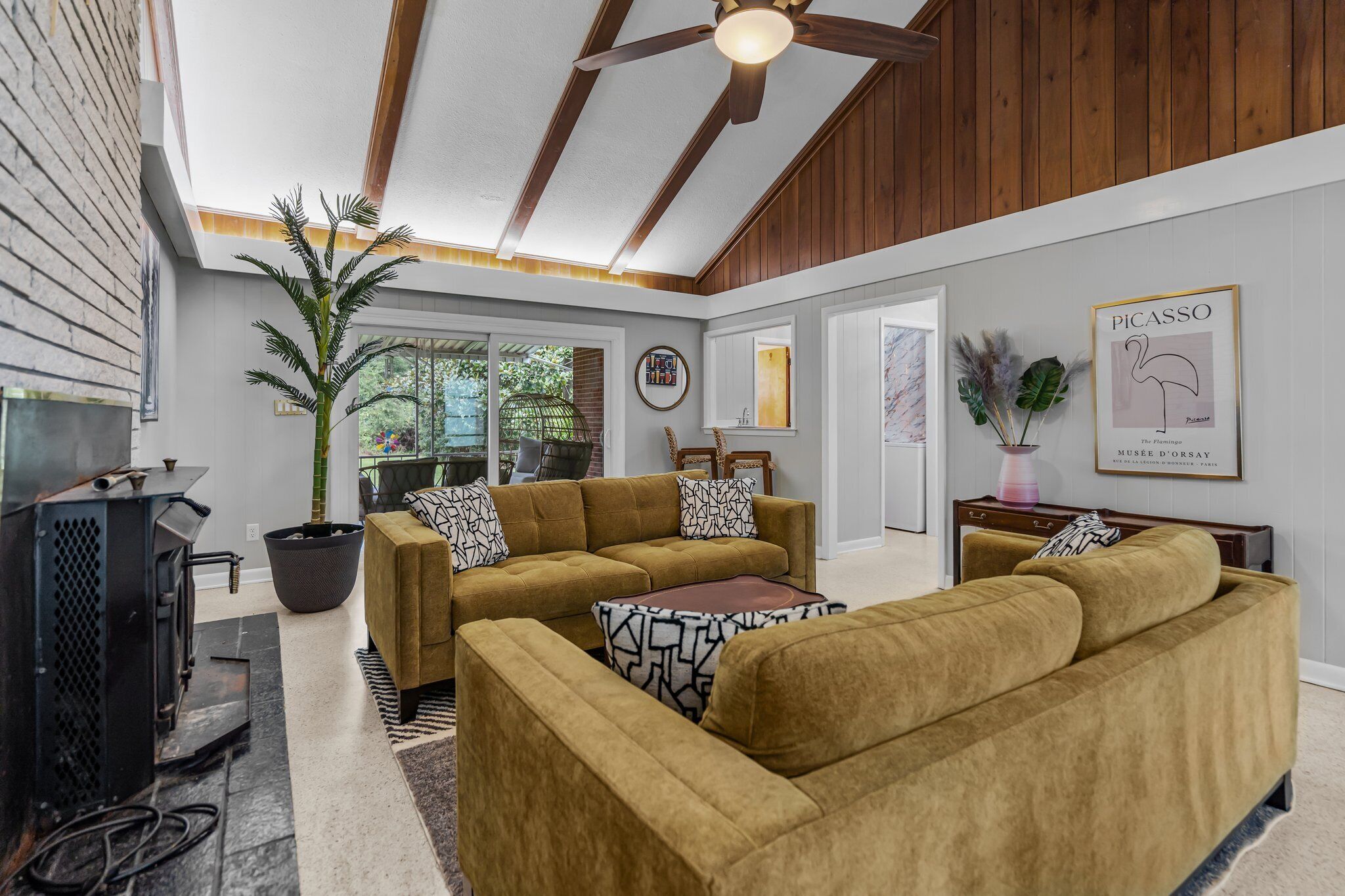 A living room with a sectional sofa, a coffee table, a television, and a ceiling fan.
