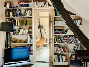 A cozy reading nook with a television, a lamp, and a bookshelf filled with books.