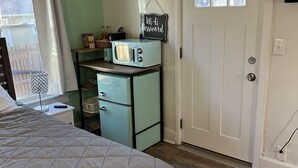 Et soveværelse med seng, et køkken i vintage-stil, en dør med et vindue og et skilt med teksten "Wi-Fi Password".