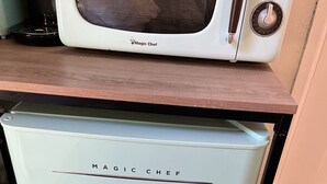 Et gammelt, hvidt Magic Chef køleskab med to døre, placeret i et køkken med en træbordplade og en mikrobølgeovn over.
