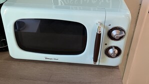 En mikrobølgeovn i vintage-stil med et sort-hvidt skilt over, der viser 'Wi-Fi password'.