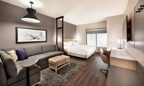 A modern hotel room with a bed, a sofa, a desk, and a large window. - Hyatt Place Munster (Munster)