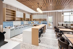 A modern kitchen with a central island, bar stools, and a dining area with tables and chairs. - Hyatt Place Munster (Munster)