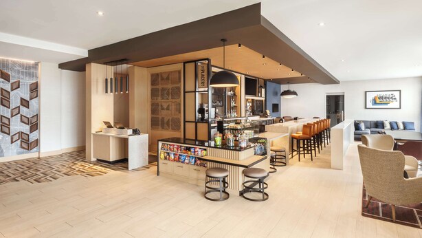 A modern bar area with a counter, stools, and a seating area with chairs and a sofa. - Hyatt Place Munster (Munster)