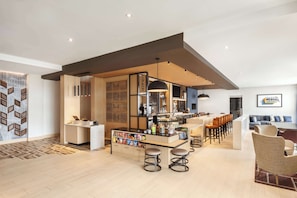 A modern bar area with a counter, stools, and a seating area with chairs and a sofa. - Hyatt Place Munster (Munster)