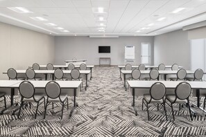 A conference room with multiple tables and chairs, a flat-screen TV, a whiteboard, and a patterned carpet. - Hyatt Place Munster (Munster)