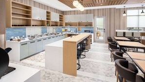 A modern kitchen with a central island, bar stools, and a dining area with tables and chairs. - Hyatt Place Munster (Munster)