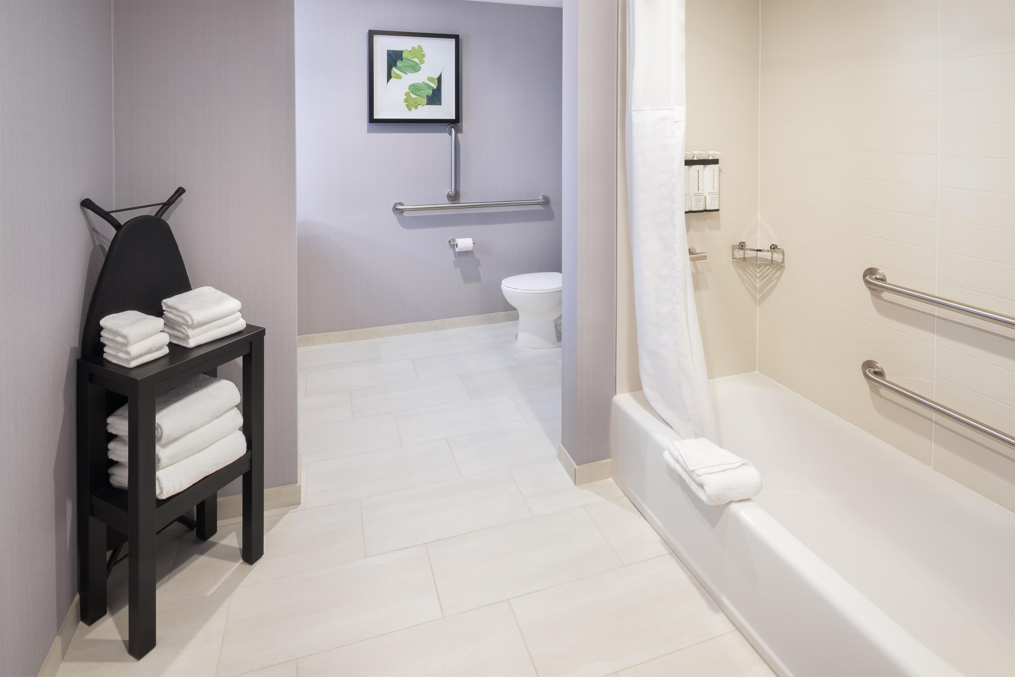 A bathroom with a bathtub, toilet, and a towel rack with folded towels.