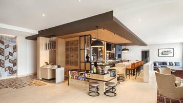 A modern bar area with a counter, stools, and a variety of snacks.