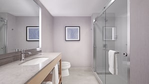 Un baño moderno con lavamanos doble, inodoro y ducha con mampara de vidrio.