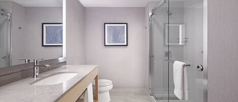 A modern bathroom with a double sink vanity, a toilet, and a glass-enclosed shower.
