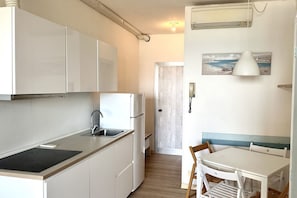 A compact kitchen with white cabinets, a sink, and a small dining table with chairs.
