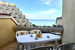 A terrace with a table set for four, overlooking a body of water.
