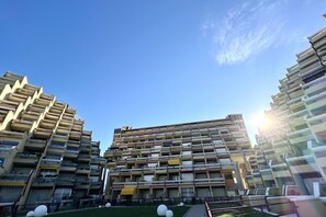 A multi-story residential building with balconies, a central courtyard, and a clear sky.