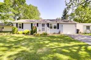Ein eingeschossiges Haus mit Veranda, Garage und gepflegtem Rasen.
