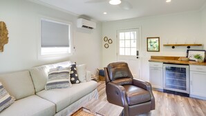 A living room with a sofa, a leather chair, a coffee table, a ceiling fan, and a kitchen area with a dishwasher. - Three Oaks Home w/ Guest House - 8 Mi to Beach! (Three Oaks)