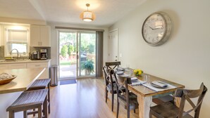 A modern kitchen with a dining area, a clock on the wall, and a view through the glass door. - Three Oaks Home w/ Guest House - 8 Mi to Beach! (Three Oaks)