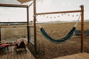 A hammock hanging in a wooden structure with a view of a grassy field and mountains. - Yurt Retreat- Unplug and Recharge! (Fort Collins)