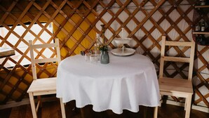 Una mesa redonda con mantel blanco, dos sillas de madera y un pequeño objeto decorativo sobre la mesa.