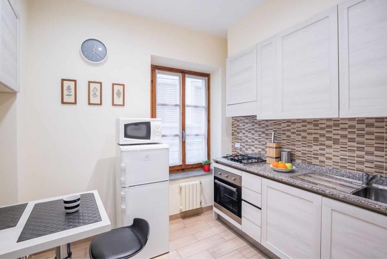 A compact kitchen with a microwave, stove, and a small dining area with a table and chair.