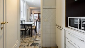 Una cucina con forno a microonde, mobili bianchi e una parete di mosaico.