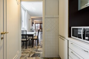 A kitchen with a microwave, white cabinets, and a tiled backsplash.