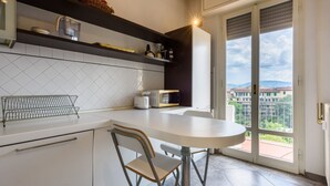 Una cocina con mostrador blanco, una silla de metal y vista a través de un vidrio.
