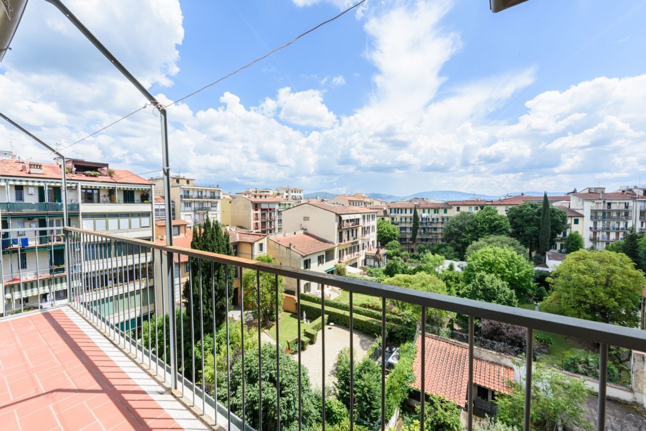 A balcony with a view of a residential area, including multi-story buildings and greenery.