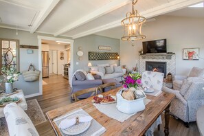 A spacious living room with a fireplace, a dining area with a wooden table, and a cozy seating area with a sofa and chairs.