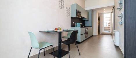 A modern kitchen with a dining area, featuring a table with chairs, a microwave, and a refrigerator.
