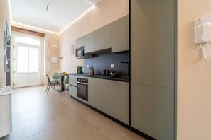 A modern kitchen with a built-in oven, microwave, and a small dining area with a table and chairs.