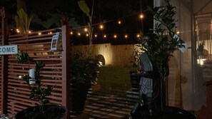 Enter a serene oasis through the charming entrance, marked by a wooden gate and lush greenery.