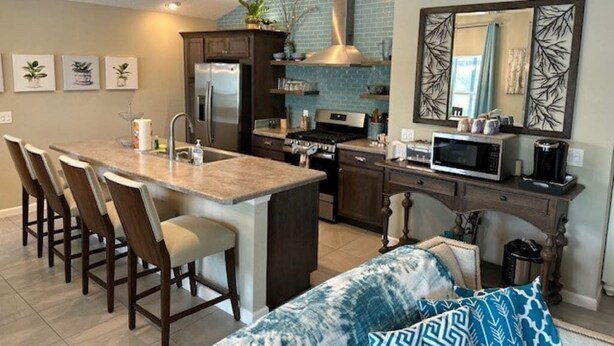 A modern kitchen with a central island, dark cabinetry, and a large mirror above the countertop. - Stay in The Villages at your pool house with cart! (Wildwood)