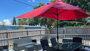 A deck with wicker furniture and a glass table, surrounded by a wooden fence. - Lovely Apartment Close to the Beach ! (Cape Canaveral)