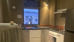 A compact kitchen with a window, a built-in oven, and a refrigerator.