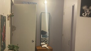 A bedroom with a bed, a dresser, a mirror, and a door.