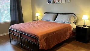 Une chambre à coucher avec un lit, deux lampes de chevet, un ventilateur de plafond et des œuvres d’art florales accrochées au mur.