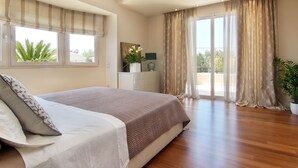 A bedroom with a large bed, a nightstand, a lamp, and a window with curtains. - Contemporary luxury villa with eclectic design a few steps away from Varkiza bay (Vari)