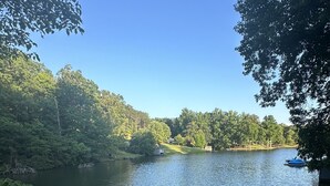 A serene lakeside view with a wooden dock extending into the water, surrounded by lush greenery and trees. - The Cove at Lake Houser-lakefront home, large deck, fishing/kayak/paddle board (Mooresboro)