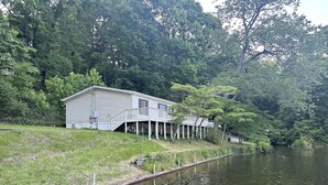 Una cabaña junto al lago con un porche y una pequeña terraza.