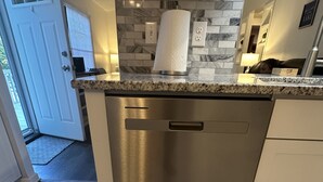 Una cocina con lavavajillas de acero inoxidable, salpicadero de mármol y encimera de granito.