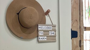 A straw hat hanging on a wall, a welcome sign, and a rustic wooden door.